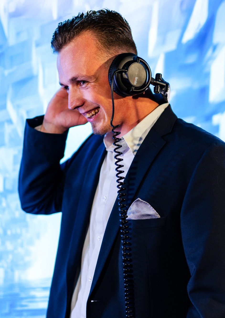 Hier ist DJ Baumi im Anzug und Kopfhörer zu sehen